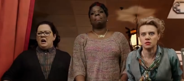 Abby, Patty, and Holtzmann stare in horror out a broken window. Caption: Abby, Patty, and Holtzmann examine the long, long list of things that happened in the closing years of the 19th century that are objectively worse than novels (or they're reading the comments on YouTube videos - it's hard to say from their expressions).